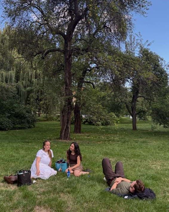 Three of us on the grass in a Prague park on a sunny afternoon, two sitting and one lying down